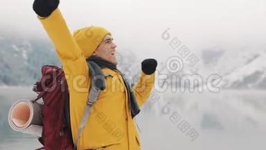 <strong>站在山顶</strong>上的年轻徒步旅行者。 旅行者举手。 成功和胜利者的概念。 冬季